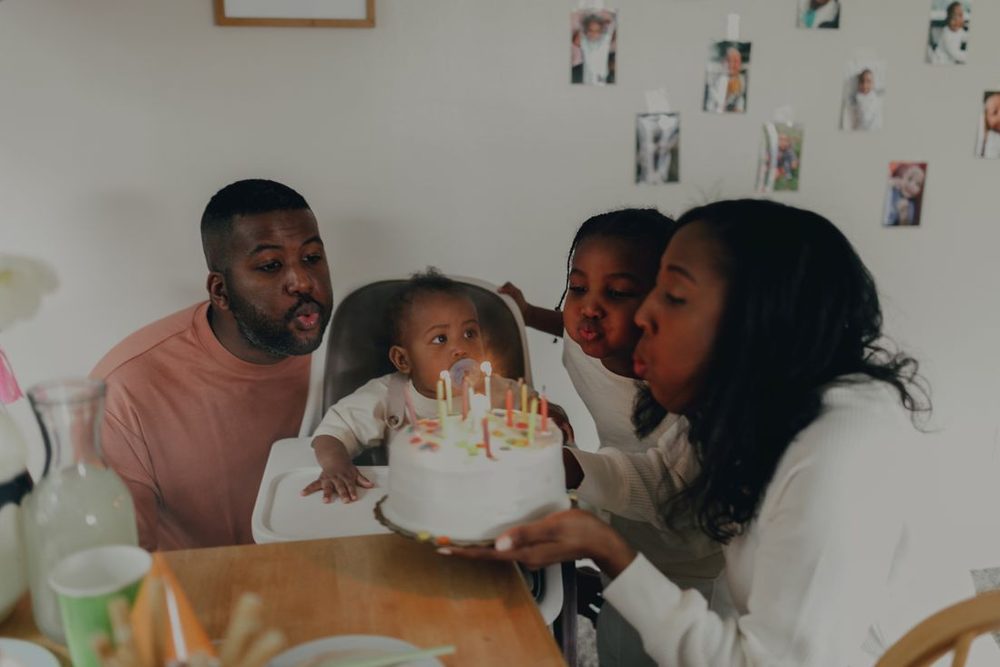 Família em volta de um bolo de aniversário com uma criança pequena