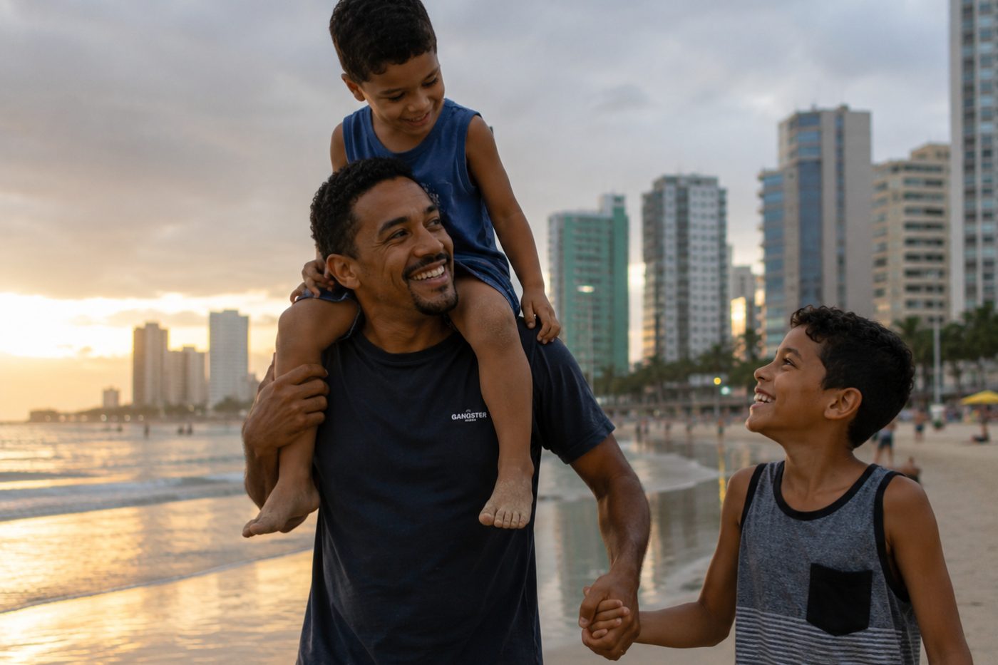 Pai andando na praia ao pôr do sol com o filho pequeno nos ombros e o filho maior de mãos dadas