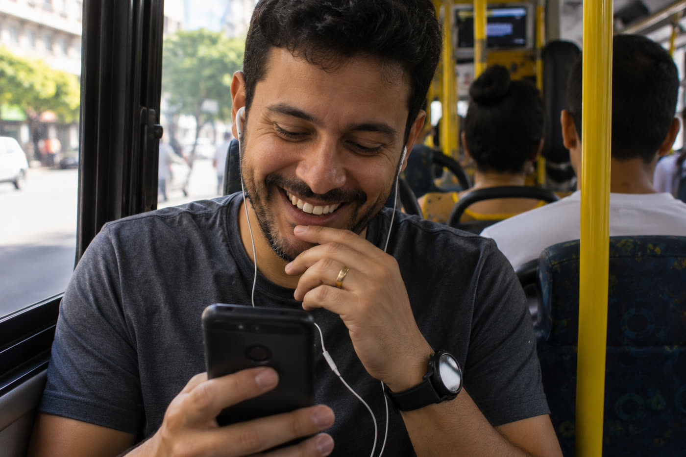 Homem sorrindo com fones de ouvido, ouvindo algo no celular dentro do ônibus